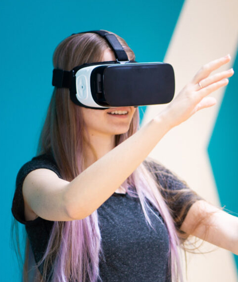 Schülerin trägt VR-Brille und bewegt die Arme